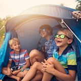 Drei Kinder sitzen in einem Zelt
