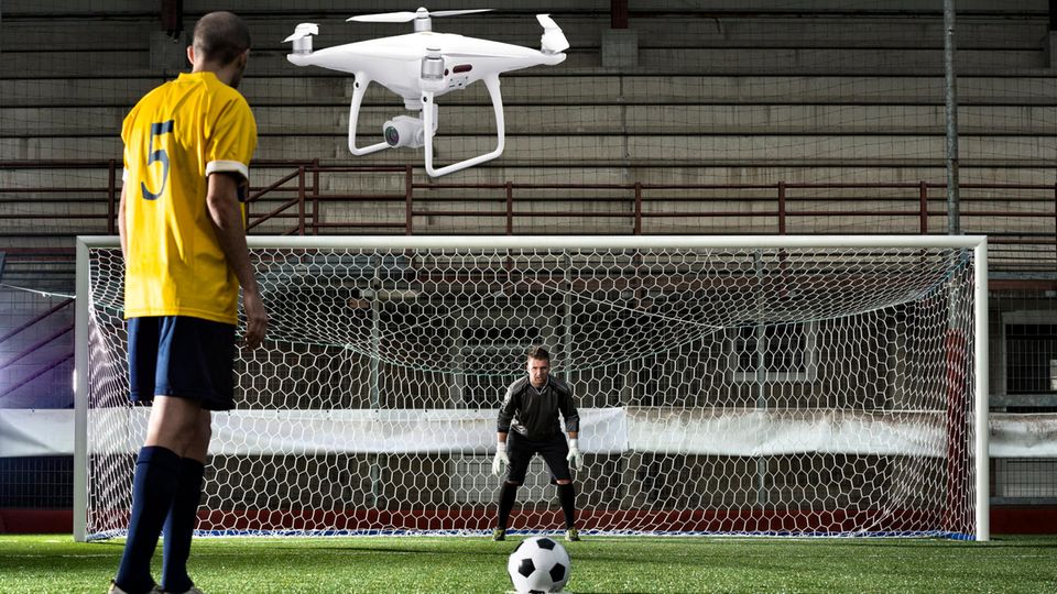 Eine Drohne fliegt neben einem Fußballspieler, der zum Elfmeter ansetzt