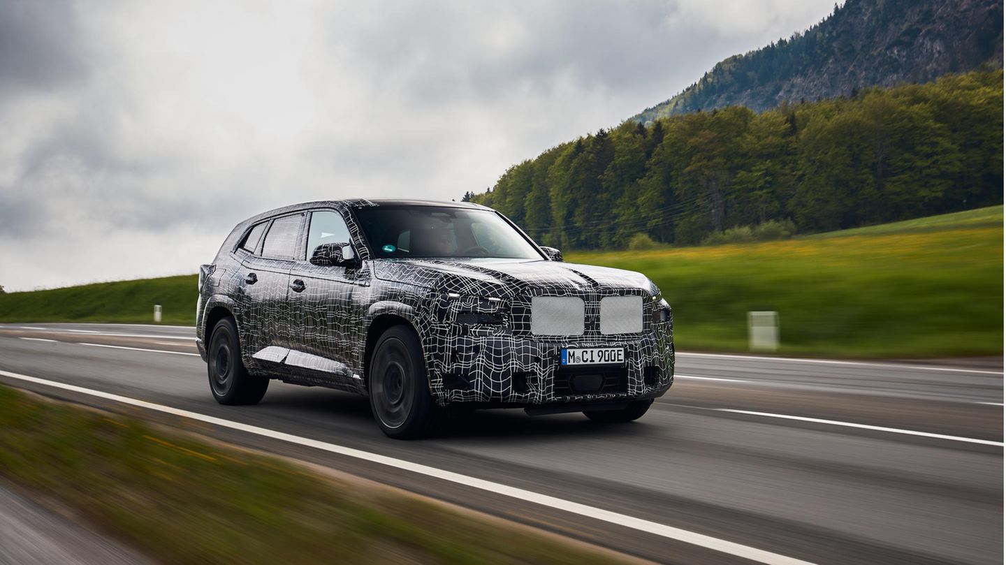 Ein BMW-Modell fährt in dunkler Tarnfolie über eine Straße