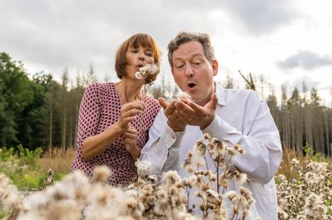 Annette Kehnel und Eckart von Hirschhausen in einer Wiese voll Pusteblumen