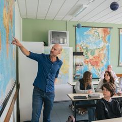 Stiftung-stern-Auslandskoordinator Marc Goergen zeigt einer Klasse auf eine Weltkarte, wo sich das afrikanische Dorf befindet