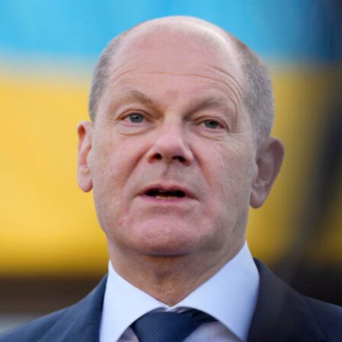 Kanzler Olaf Scholz vor blau-gelbem Hintergrund