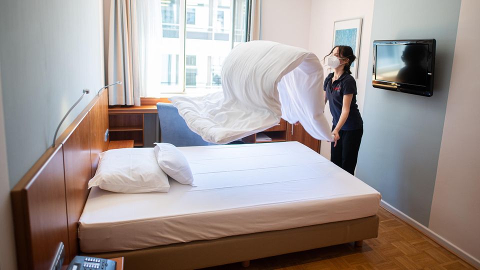 Eine Frau macht in einem Hotelzimmer das Bett