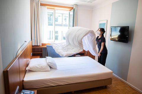 Eine Frau macht in einem Hotelzimmer das Bett