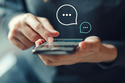 Eine Frau hält ein Smartphone in der Hand und chattet