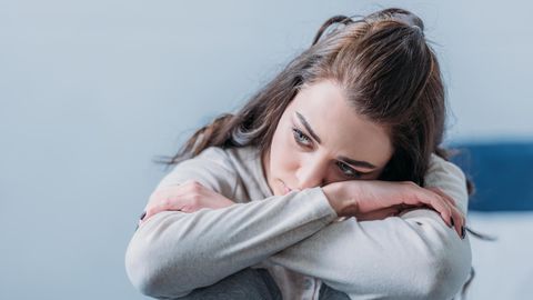 Laufen und Depression: Eine traurige Frau sitzt am Boden