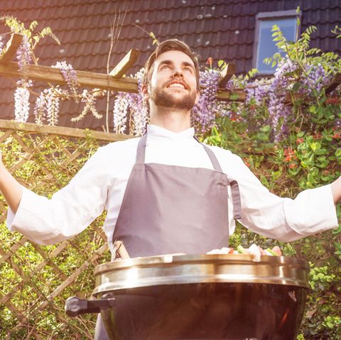 Männer am Grill: Ein Mann erhebt die Hände beim Grillen.
