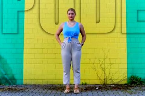 Youtuberin DominoKati steht vor einer Wand – über ihr die Aufschrift "Lipödem"