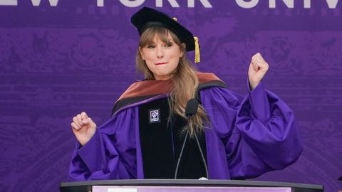 Taylor Swift in Robe und mit Absolventen-Hut vor einem Rednerpult