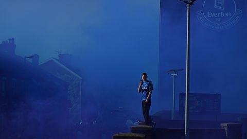 Ein Everton-Anhänger steht auf einem Dach inmitten von blauem Rauch