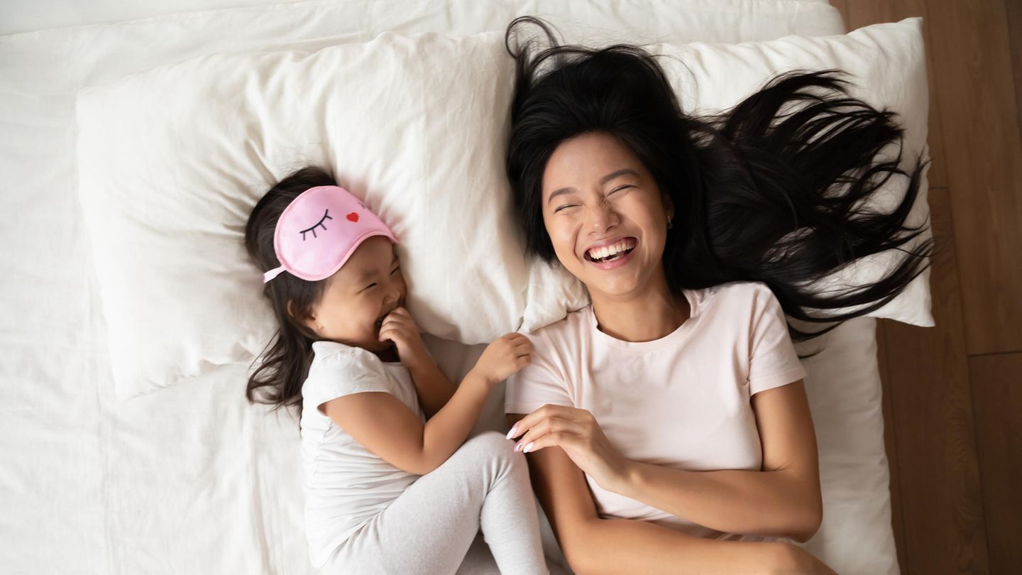 Mutter und Tochter liegen lachend im Bett