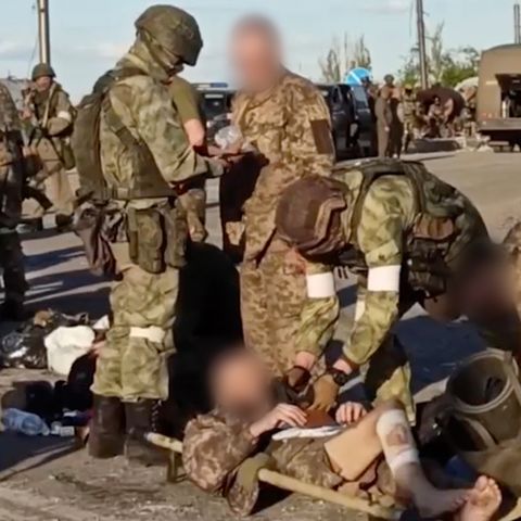 Russische Soldaten, die ukrainische Soldaten durchsuchen