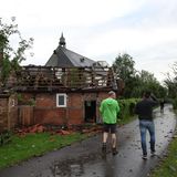 Menschen stehen vor einem beschädigten Haus