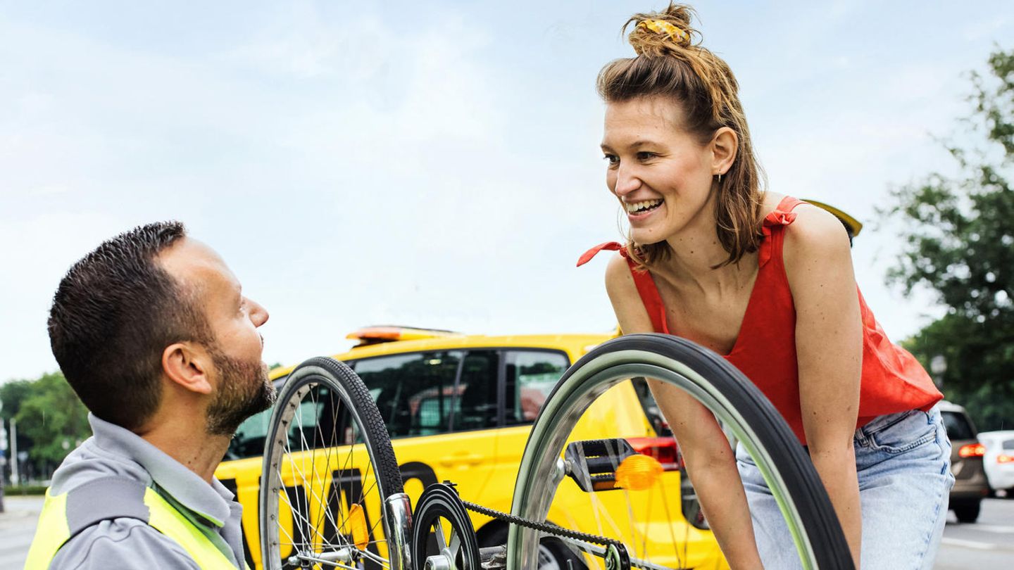 Ein ADAC-Fahrer hilft einer Frau bei der Reparatur ihres Fahrrads
