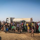 Menschen stehen an einem Tank-Lastzug zur Ausgabe von Wasser an