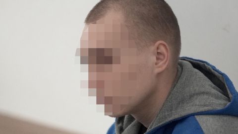 Ein junger weißer Mann mit eingefallenen Wangen und kurz rasierten Haaren sitzt in blau-grauem Pullover im Gerichtssaal