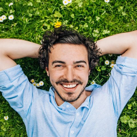 Ein Mann liegt im Gras und lächelt