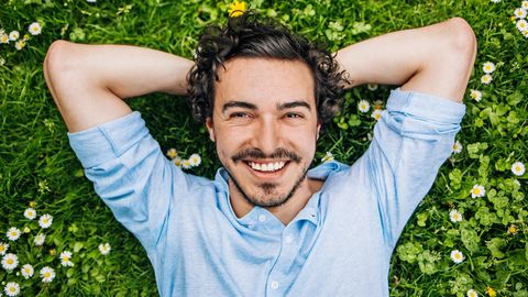 Ein Mann liegt im Gras und lächelt