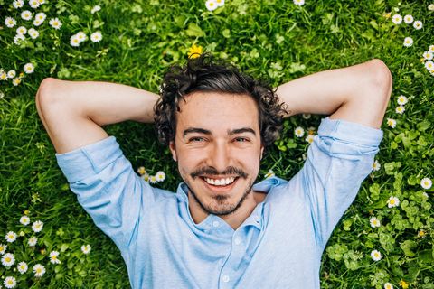 Ein Mann liegt im Gras und lächelt