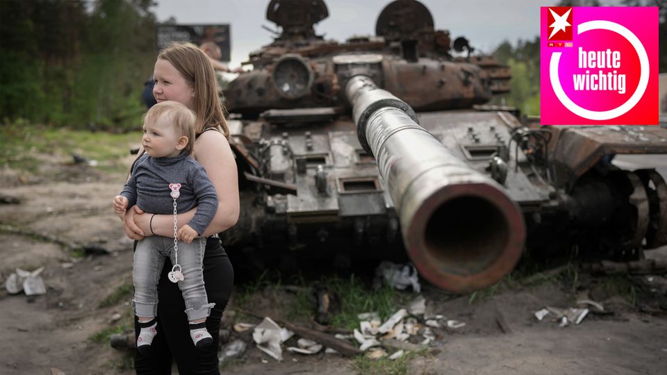 Eine Frau und ein Kind posieren vor einem zerstörten russischen Panzer in der Ukraine