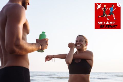 Sport im Urlaub: Ein Mann und eine Frau dehnen sich am Strand