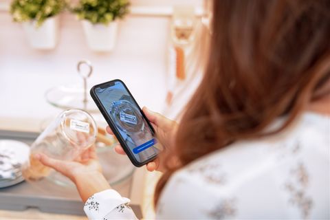 Eine Frau scannt einen Artikel mit ihrem Smartphone ein