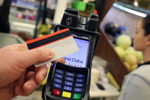 Eine Person hält ihre EC-Karte vor ein Kartenterminal