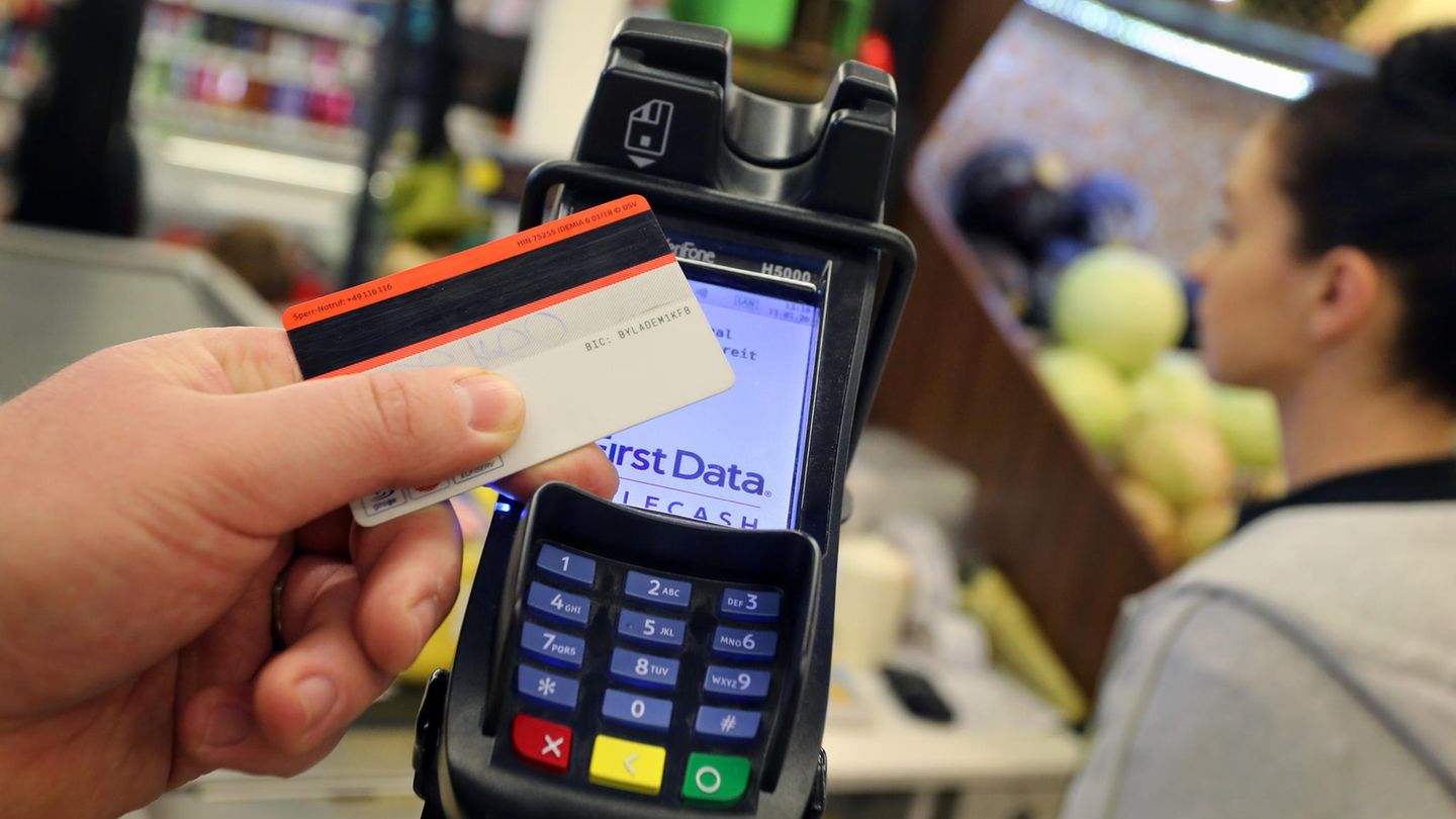 Eine Person hält ihre EC-Karte vor ein Kartenterminal