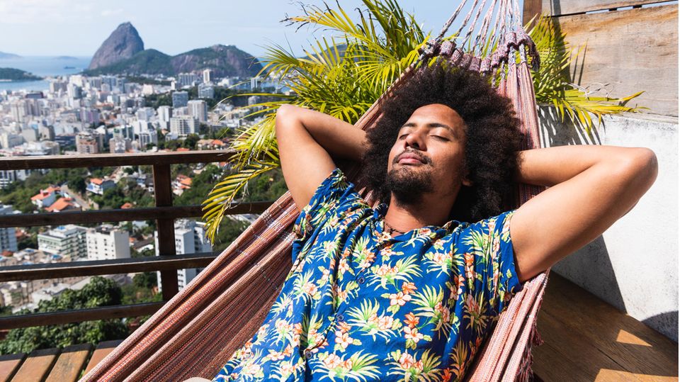 Ein Mann liegt im Hawaiihemd im Liegestuhl und genießt die Sonne.