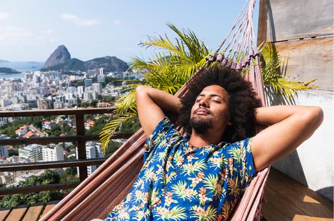 Ein Mann liegt im Hawaiihemd im Liegestuhl und genießt die Sonne.