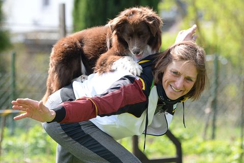 Uta Opel trainiert mit ihrem Rüden Takutai für eine Choreographie in der Sportart Dogdance. Der Hund liegt auf ihrem Rücken.