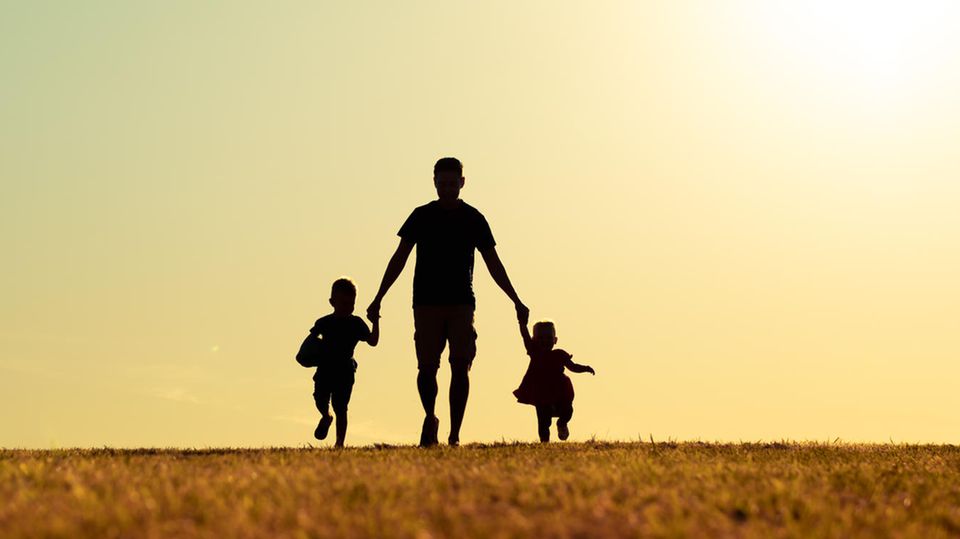 Vatertag: Ein Vater mit Sohn und Tochter im Park bei Sonnenuntergang