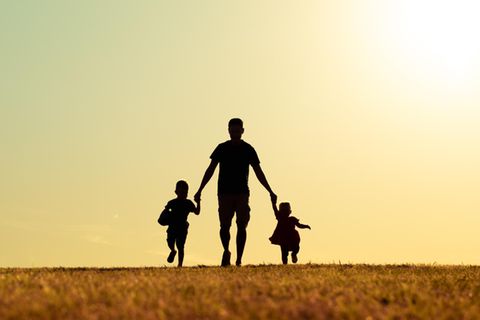 Vatertag: Ein Vater mit Sohn und Tochter im Park bei Sonnenuntergang