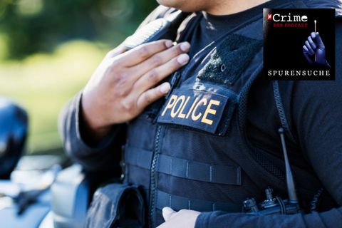 Beschnittene Ansicht eines jungen Polizisten, der vor seinem Streifenwagen steht.