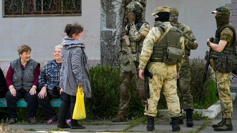 Ältere Anwohner sprechen in Cherson mit einer Gruppe russischer Soldaten