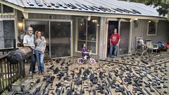 Eine Familie steht auf ihrer Veranda, der Boden ist übersäht mit Waffen.