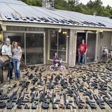 Eine Familie steht auf ihrer Veranda, der Boden ist übersäht mit Waffen.
