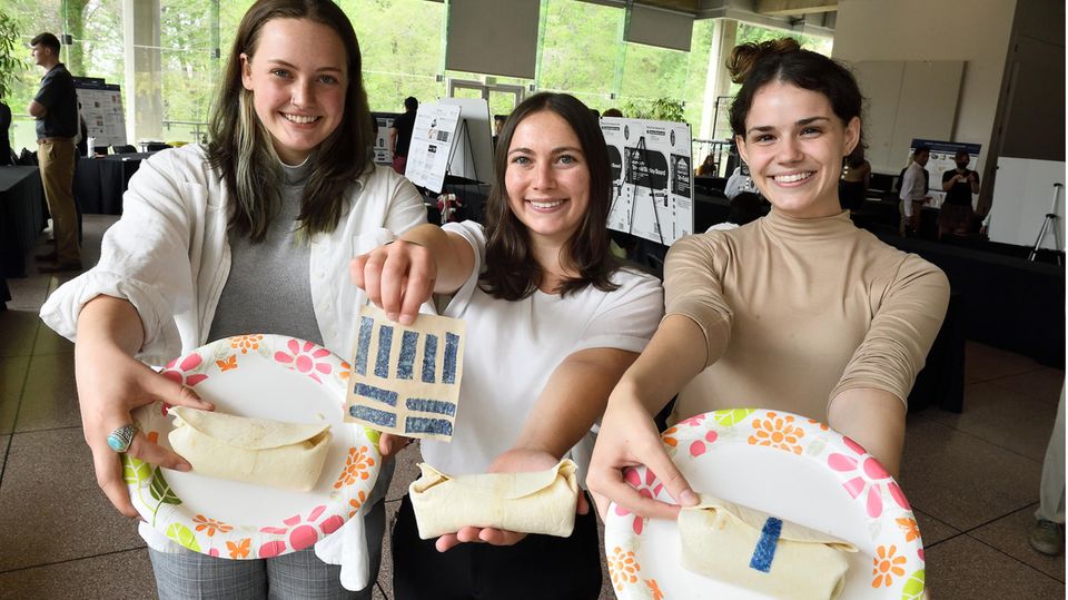 Erin Walsh, Tyler Guarino und Marie Eric zeigen mit essbarem Klebeband zugeklebte Burritos
