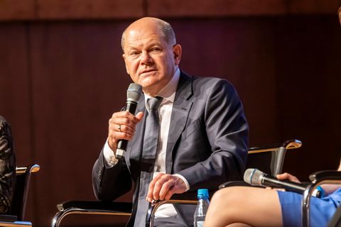 Olaf Scholz mit einem Mikrofon in der Hand.