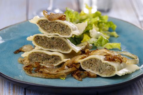 Geschmelzte Maultaschen mit Zwiebeln liegen neben einem Blattsalat auf einem Teller