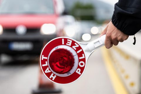 Polizist hält Kelle mit der Aufschrift "Halt Polizei" in der Hand
