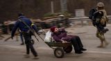 Ein ukrainischer Soldat und ein Milizionär helfen einer Familie bei der Flucht über den Fluss Irpin