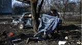 Ein Mann deckt einen Zivilisten zu, der beim Beschuss von Tschuhujiw durch russische Truppen getötet wurde