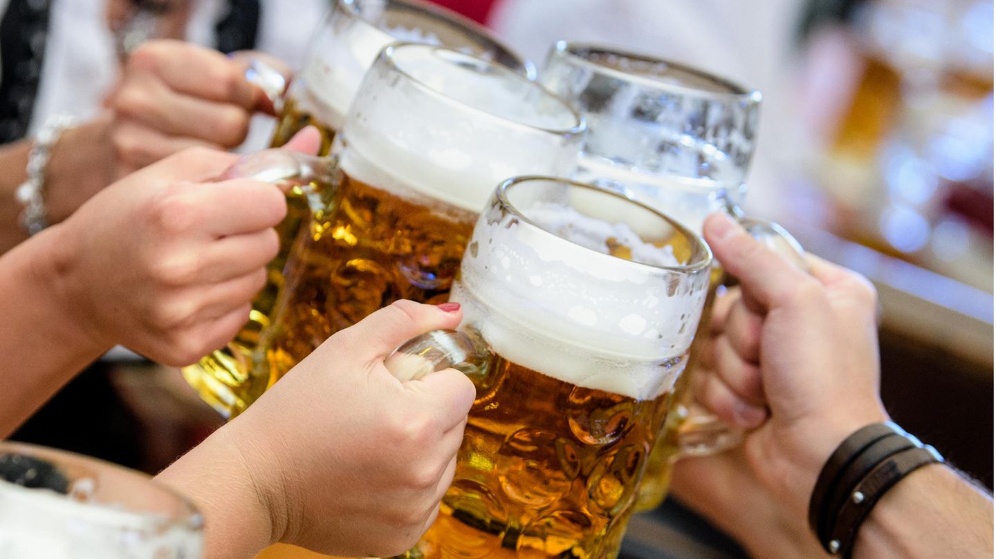Mehrere volle Bierkrüge werden beim Oktoberfest zusammengestoßen