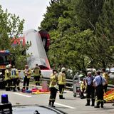 Feuerwehrmänner stehen an der Unglücksstelle, zahlreiche Opfer müssen aus den entgleisten Waggons geborgen werden. Zwei Waggons am Ende des Zugs liegen wie umgeworfen neben den Gleisen an einem kleinen Abhang.