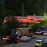 Auf einer mehrspurigen Straße stehen zahlreiche Fahrzeuge von Polizei, Feuerwehr und THW. Dahinter eine Lok und zwei Waggons