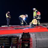Mehrere Feuerwehrleute stehen mit Vorschlaghammer auf der Seitenwand eines umgekippten Waggons herum