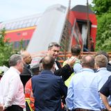 Am Samstagmorgen macht sich auch Bayerns Ministerpräsident Markus Söder (M.) ein Bild von der Situation an der Unglücksstelle – und spricht von einem "Stich ins Herz", den das Unglück ihm versetzt habe. Er sagt: "Man muss sich das jetzt so vorstellen: Es ist kurz vor den Ferien, im Zug ausgelassene Stimmung, in einer der schönsten Regionen, die Bayern ja hat - und dann passiert so was und verändert möglicherweise ein Leben komplett."