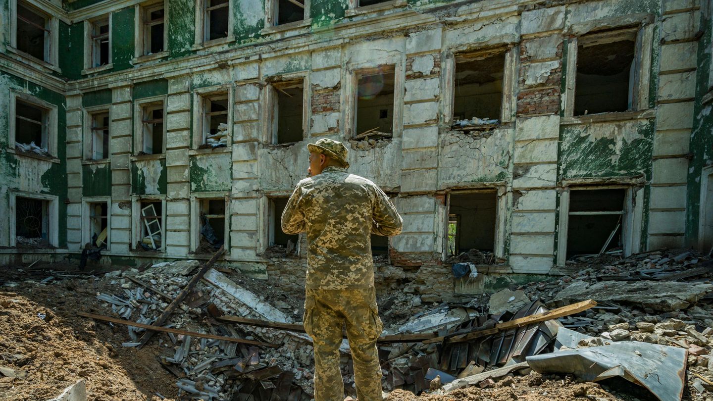Ein ukrainischer Soldat steht vor einem Bombenkrater an einer Schule in Kostjantyniwka