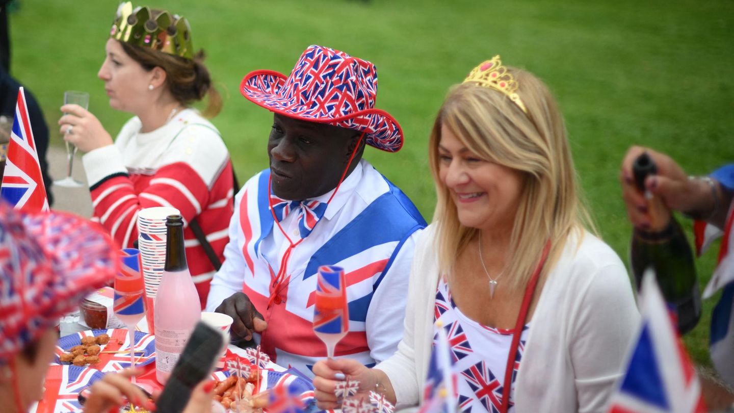 Smiling people sit around a table decorated with Union Jacks for a picnic